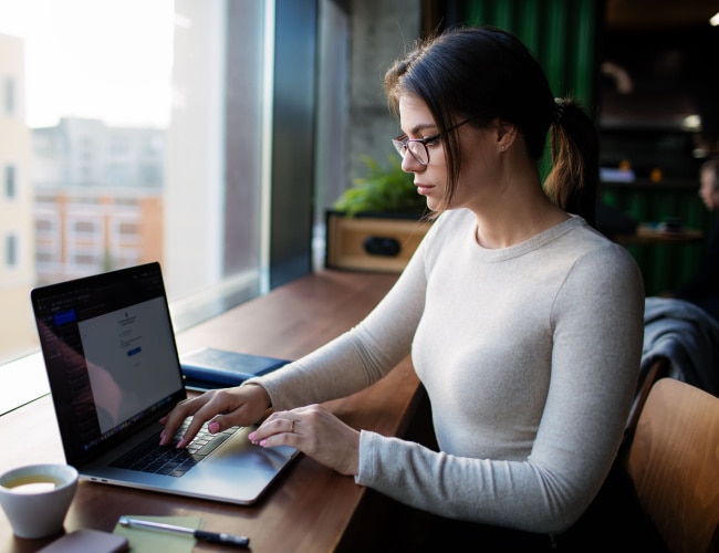 Laptop user working on business tasks at a cozy coffee shop.