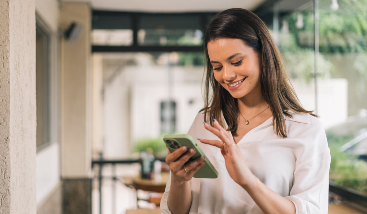 Smiling woman using smartphone outdoors on patio.
