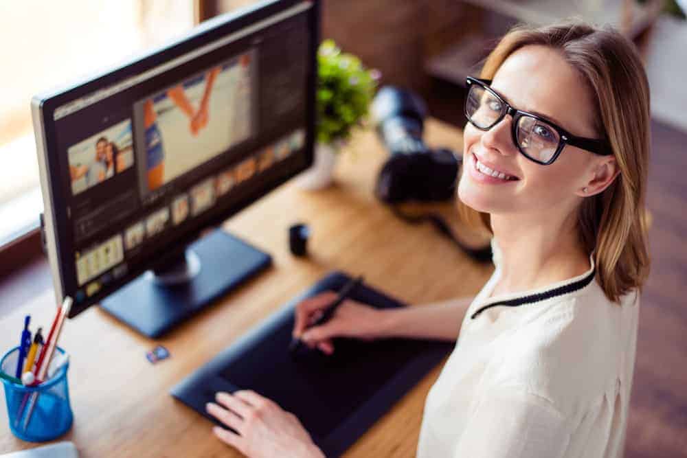 Bright female designer working on photo editing at desktop computer.