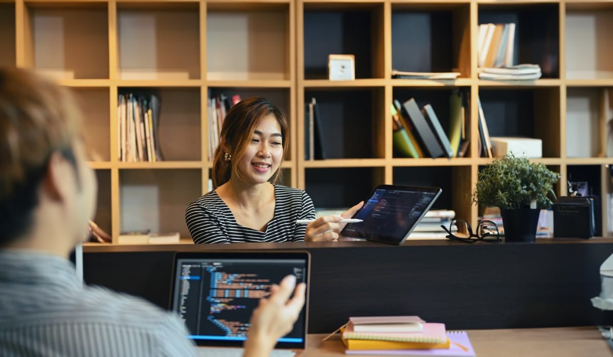 Collaborative tech meeting at Hozio, Inc. office with professionals sharing digital ideas and data on tablets and laptops.