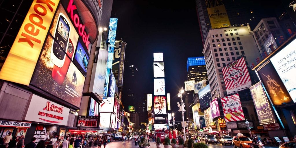 Vibrant Times Square at night with bright digital billboards and bustling crowds.