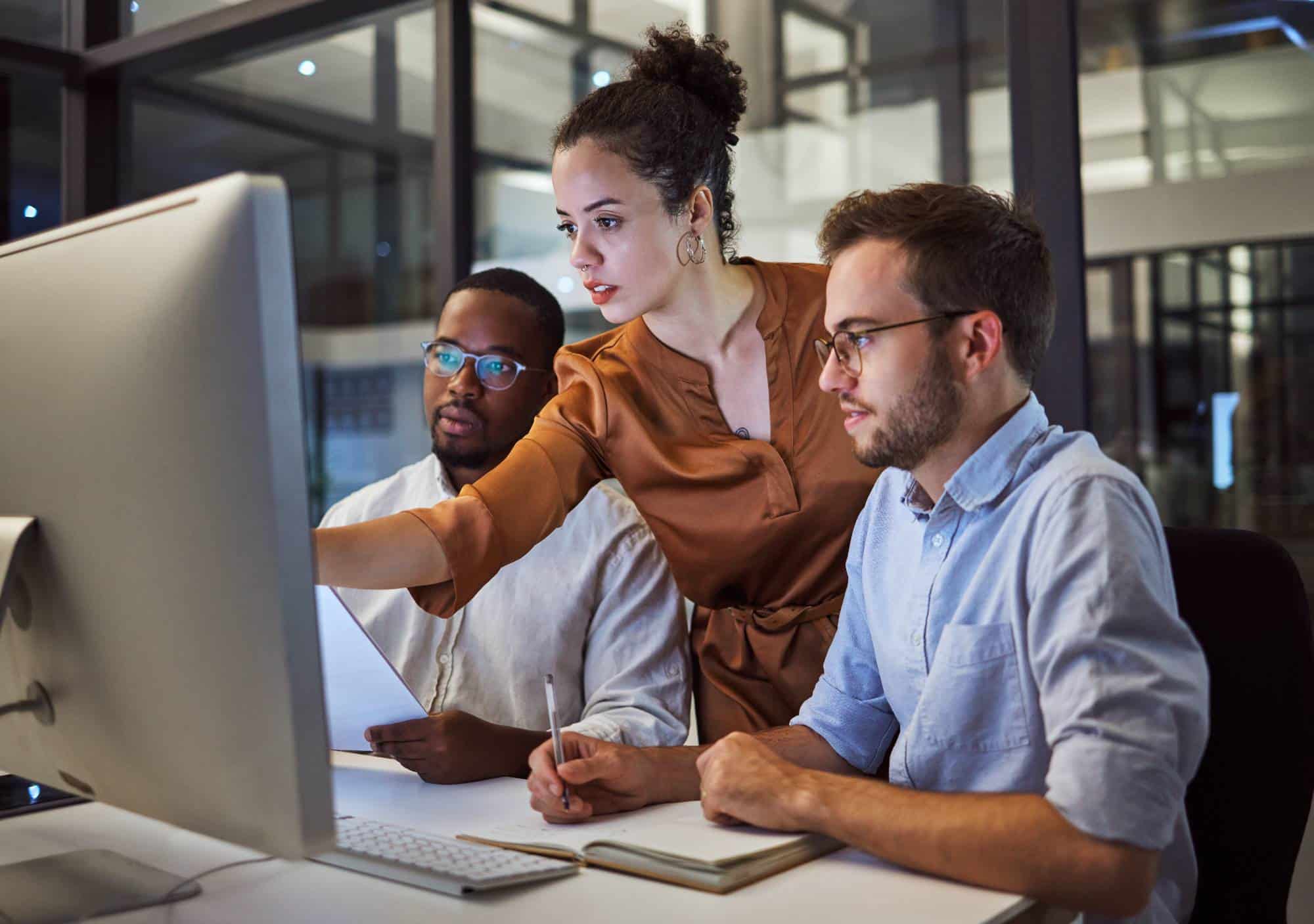 Team collaborating on a project at a modern office computer workstation.
