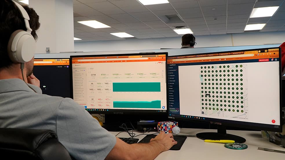 Hozio office worker analyzing data on dual monitors during remote work setup.