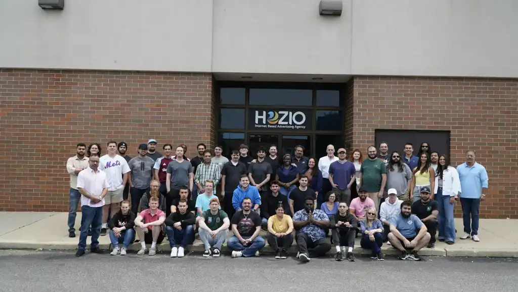 Large diverse team of employees outside Hozio office building, a leading internet advertising agency.